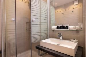 巴黎驿站酒店的一间带水槽和玻璃淋浴的浴室