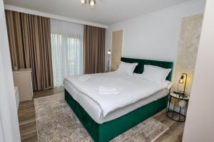 坎普朗莫道尼斯Bucovina Flower的一间卧室配有一张白色大床和绿色床头板