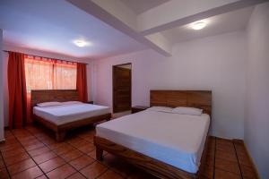 福尔图纳Villa El Bosque La Fortuna的一间卧室设有两张床和窗户。