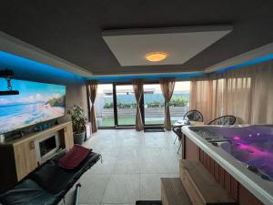 奥拉迪亚Jacuzzi Home的一间带浴缸和电视的客厅