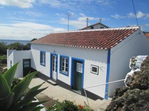 Porto Judeu昆提哈达奇拉度假屋的一间白色的小房子,设有蓝色的门
