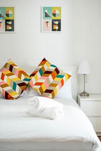 布里斯托Charming 1 bedroom apartment (+ sofa bed) in Central Bristol的卧室配有白色的床和色彩缤纷的枕头