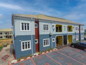拉各斯AJI Warm 2BED Apartment (Ijegun, Lagos)的蓝色和白色的建筑,停车场有车