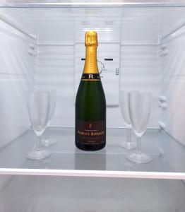 埃佩尔奈Groom Épernay - Le Petit Tonnelier的冰箱里的一瓶香槟和两杯