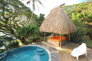 萨武萨武Beachfront Villa - House of Bamboo, Infinity Pool的游泳池旁设有椅子和小屋