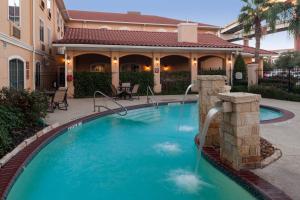 圣安东尼奥圣安东尼奥机场万豪唐普雷斯套房酒店的一座房子前面带喷泉的游泳池