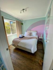 圣雷莫Salty Paws Dog Friendly Luxe Cottage的一间卧室配有一张带紫色床头板的床
