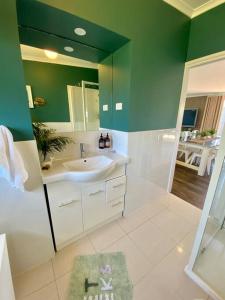 圣雷莫Salty Paws Dog Friendly Luxe Cottage的一间带水槽和绿色墙壁的浴室