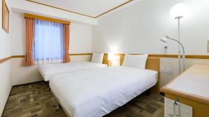 东京Toyoko Inn Tokyo Tozai-sen Nishi-kasai的酒店客房设有两张床和窗户。