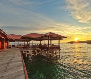 WaisaiCoriana Dive Resort的日落时分在水面上设有餐厅的码头