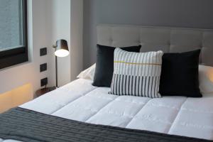 墨西哥城Punto Lofts Periférico Sur的卧室内的一张带黑色枕头的白色床