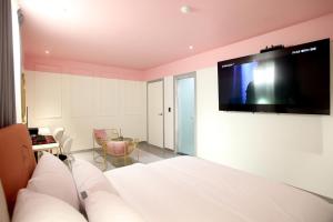 GimcheonBaba Hotel Gimcheon的卧室配有一张壁挂式平面电视的床。