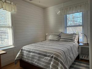 格洛斯特Retreat near Beaches的一间卧室配有带条纹被子的床和2扇窗户