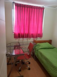 塔尔卡Departamento en Alameda Talca的一间卧室配有书桌和一个带粉红色窗帘的窗户。