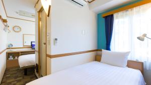 横滨Toyoko Inn Yokohama Stadium Mae No 1的一间卧室配有一张床、一张书桌和一个窗户。
