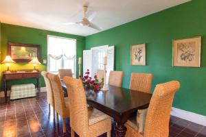 总督港Folly home的一间拥有绿色墙壁和木桌及椅子的用餐室
