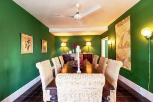 总督港Folly home的一间拥有绿色墙壁和桌椅的用餐室