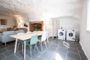 吕讷Maison troglodyte - Le Cerisier Perché的厨房以及带桌子和洗衣机的客厅。