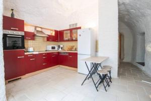 吕讷Maison troglodyte - Le Cerisier Perché的厨房配有红色橱柜和白色冰箱