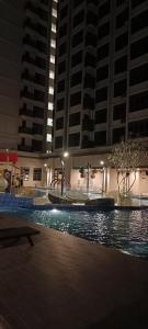 马六甲bali residensi的一座拥有高楼建筑的夜间游泳池