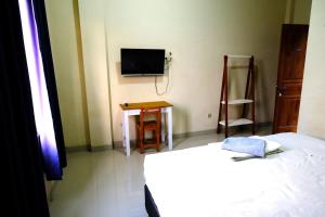 NgabeanDANGAU DATUK GUESTHOUSE的卧室配有一张床,墙上配有电视。