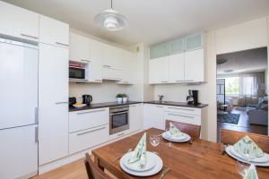 瓦萨Kotimaailma Apartments Vaasa的厨房以及带白色橱柜和木桌的用餐室。