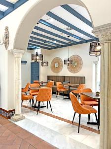 塞维利亚Itaca Sevilla by Soho Boutique的用餐室配有橙色椅子和桌子