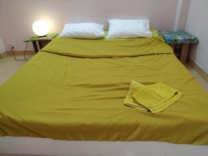 胡志明市Entire small house mins to everywhere!的一张带黄色毯子和两个枕头的床