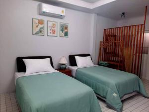 甲米镇Bann Kam B&B的一间卧室配有两张床和一张婴儿床。