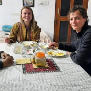 阿尔瓦尔Travel curiosity Homestay的坐在餐桌旁吃食物的男人和女人
