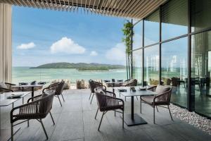 哥打京那巴鲁Hyatt Centric Kota Kinabalu的一间带桌椅的海景餐厅