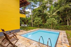 彼得罗波利斯Sítio Borges的一个带椅子的游泳池和一个黄色的房子