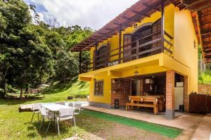 彼得罗波利斯Sítio Borges的黄色的房子,配有桌子和椅子