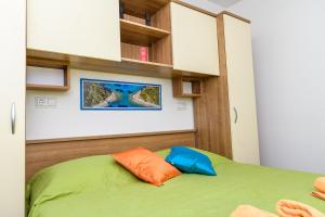 木洛希尼Villa Magnolia的一间卧室配有绿色的床和橙色和蓝色枕头