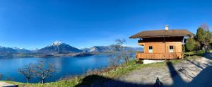 锡格里斯维尔CHALET EGGLEN "Typical Swiss House, Best Views, Private Jacuzzi"的水体旁的山丘上的建筑物
