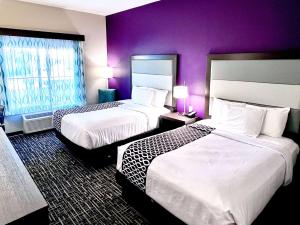 法尔La Quinta by Wyndham Pharr North McAllen的紫色墙壁的酒店客房内的两张床