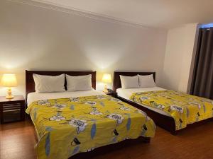 胡志明市Phung Long Hotel的酒店客房带两张带黄床单的床