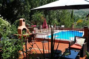 格拉纳达Cortijo La Mata的一个带遮阳伞和桌椅的游泳池