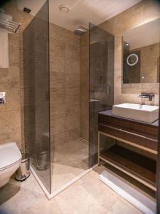 普里什蒂纳Emery Hotel的带淋浴、盥洗盆和卫生间的浴室