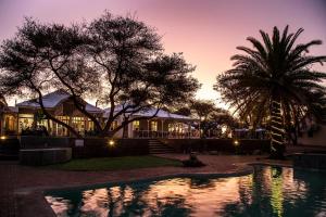 奥奇瓦龙戈Otjibamba Lodge的日落时分带游泳池的别墅