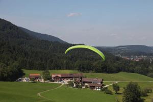 巴特维塞Gästehaus Kleinbuch的绿色降落伞飞过田野中的房屋