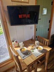 卡纳芬Elephant View Shepherds Hut的挂在木桌上并放着碗的食物的电视机