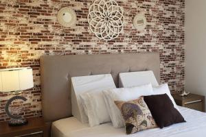 HernandariasPAZ Y ARMONÍA: un hogar lejos de casa!的一间卧室设有砖墙和一张带枕头的床