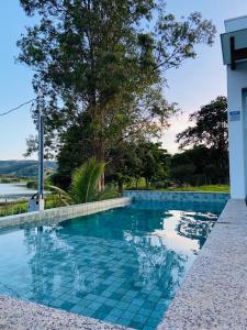 卡皮托利乌Pousada Vila do Lago的一座位于房子前方的蓝色瓷砖游泳池
