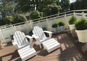 米兹多洛杰Playa Baltis Apartamenty Club di Mare的两把白色椅子坐在种有盆栽植物的甲板上