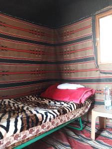 Al KhuraybahFeynan wild camp的一张位于带条纹墙的房间的床铺