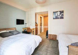 福冈LINK HOUSE HOTEL - スマート無人ステイ - Unmanned design hotel的一间卧室配有两张床、一张桌子和一台电视。