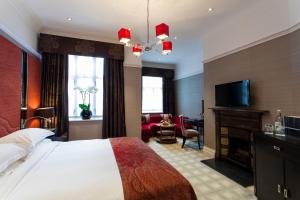 伦敦The Capital Hotel, Apartments & Townhouse的一间卧室配有一张床、一个壁炉和一台电视。