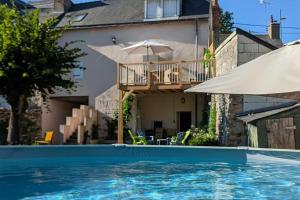 BaugéLogis des Fées, spa, piscine et jardin的一座带遮阳伞的游泳池的房子