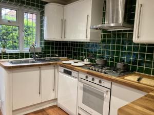 布伦特伍德Brackens的厨房配有白色橱柜和绿色瓷砖